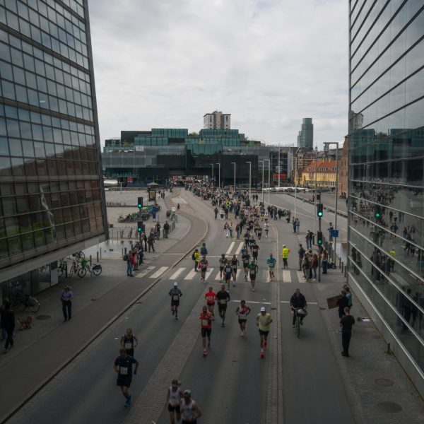 Copenhagen Marathon runners passing between modern glass buildings