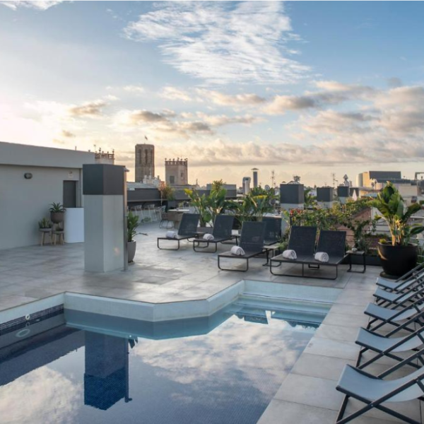 Rooftop swimming pool and sun loungers at the Silken Ramblas Hotel in Barcelona, with city views at sunset.